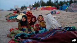 지난달 29일 아프가니스탄 어린이들이 재난당국 주변 난민촌에서 담요로 추위를 피하고 있다. 