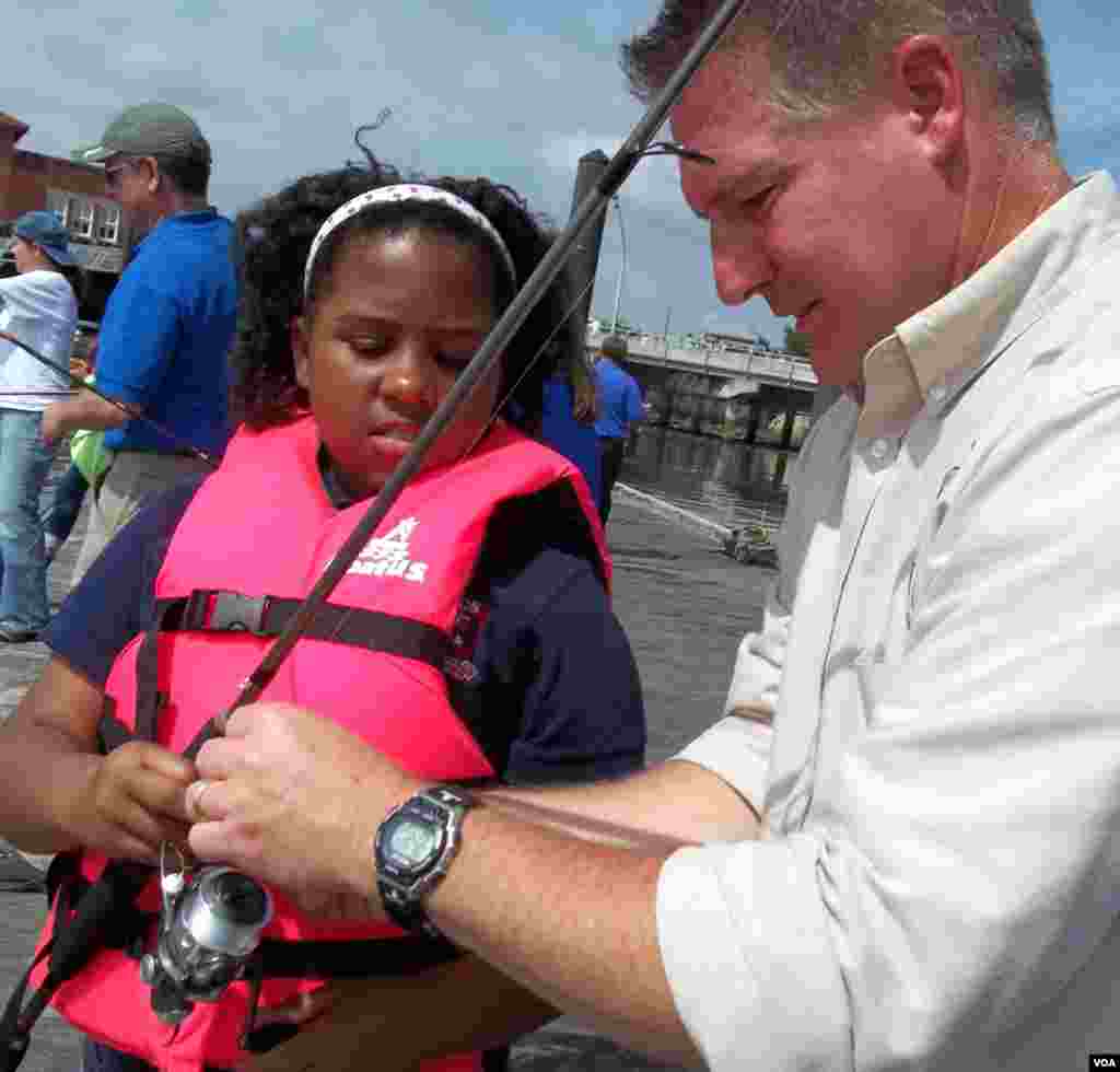 U.S. Fish and Wildlife Service volunteer Eric Lawton gives Makayla Gray her first fishing lesson on the Anacostia. (Rosanne Skirble/VOA)