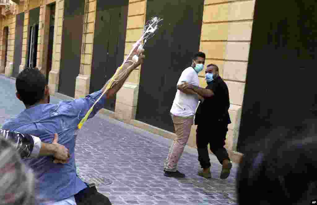 A bank customer throws eggs toward the guards of a bank, during a protest in Beirut, demanding that they be allowed to withdraw their deposits that have been blocked amid Lebanon's severe financial and economic crisis.&nbsp;