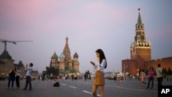 FILE - A young woman checks her smartphone at Red Square in Moscow, Russia, July 25, 2016. Russians may haver their access to Facebook blocked if the social media giant does not start storing Russian user data locally.