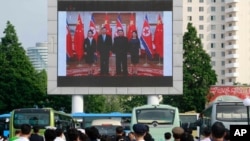지난 2019년 6월 북한 평양역 광장에 설치된 대형 화면에서 북한 김정은 국무위원장이 중국에서 시진핑 주석 부부와 만난 소식이 나오고 있다.