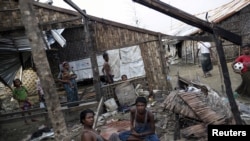 FILE - Rohingya people pass their time in a damaged shelter in a Rohingya displaced-persons camp outside Sittwe, Rakhine state, Myanmar, Aug. 4, 2015