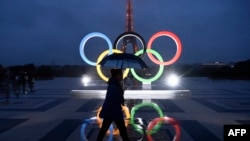 На цьому фото жінка проходить на фоні Олімпійських кілець у Парижі 13 вересня 2017 р. після того, як Міжнародний олімпійський комітет оголосив Париж містом-господарем літніх Олімпійських ігор 2024 р. Фото: CHRISTOPHE SIMON / AFP