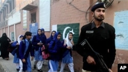 A Pakistani police officer stands guard as children make their way to school in Lahore, Pakistan, Monday. Pakistani authorities closed schools last week, in the country's largest province, Punjab, following warnings of possible militant attacks. The U.S. will give Pakistan over $800 million in foreign aid in 2016. (AP Photo/K.M. Chaudary)