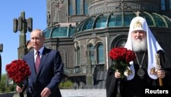 რუსეთის პრეზიდენტი ვლადიმირ პუტინი (მარცხნივ) და პატრიარქი კირილე (მარჯვნივ) რუსეთის არმიის საკათედრო ტაძართან. 22 ივნისი, 2020 წელი.