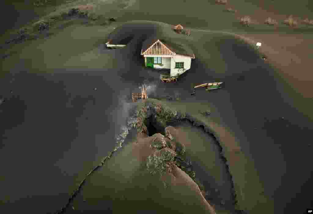 A fissure is seen next to a house covered with ash on the Canary island of La Palma, Spain.