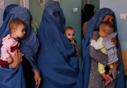 FILE - In this Aug. 26, 2019 photo, mothers hold their babies suffering from malnutrition as they wait at a UNICEF clinic in Jabal Saraj, north of Kabul, Afghanistan.