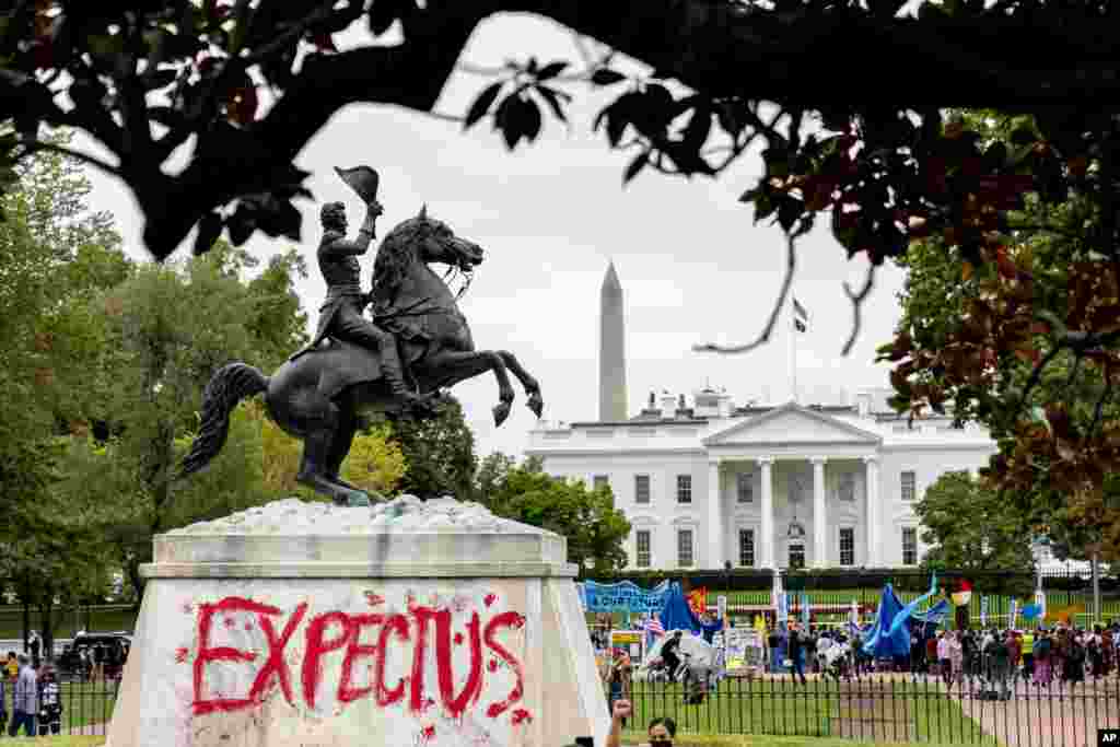 The words "Expect Us" are spray-painted on the base of the Andrew Jackson statue in Lafayette Park as Indigenous and environmental activists protest in front of the White House in Washington.