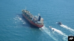 In this photo released Monday, Jan. 4, 2021, by Tasnim News Agency, a seized South Korean-flagged tanker is escorted by Iranian Revolutionary Guard boats on the Persian Gulf. (Tasnim News Agency via AP)