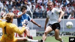 អ្នកចាំទីអាល្លឺម៉ង់ Harald Schumacher (ឆ្វេង) និង​​​ខ្សែ​​​ការពារ Hans-Peter Briegel (ស្តាំ) រារាំង​​​ការ​​​ស៊ុត​​​បញ្ចូល​​​ទី​​​របស់​​​កីឡាករ​​​បារាំង William Ayache ក្នុង​​​ការ​​​ប្រកួត​​​បួន​​​ក្រុម​​​ចុង​​​ក្រោយ​​​នៅ​​​ World Cup ឆ្នាំ​​​១៩៨៦ ក្នុង​​​ទីក្រុង​​​ប្រទេសម៉ិកស៊ិក