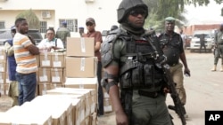 A police officer stands guard as electoral workers load ballot papers into trucks to be transported to polling stations, at the Independent National Electoral Commission in Yola, Nigeria, Feb. 15, 2019.