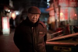 This picture taken on Feb. 16, 2017 shows an elderly man - part of a migrant work force that keeps the economy running, walking on a street in the Heiqiaocun village in Beijing.