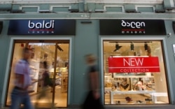 FILE - People pass by a shop window on a street in Tbilisi, June 4, 2013.