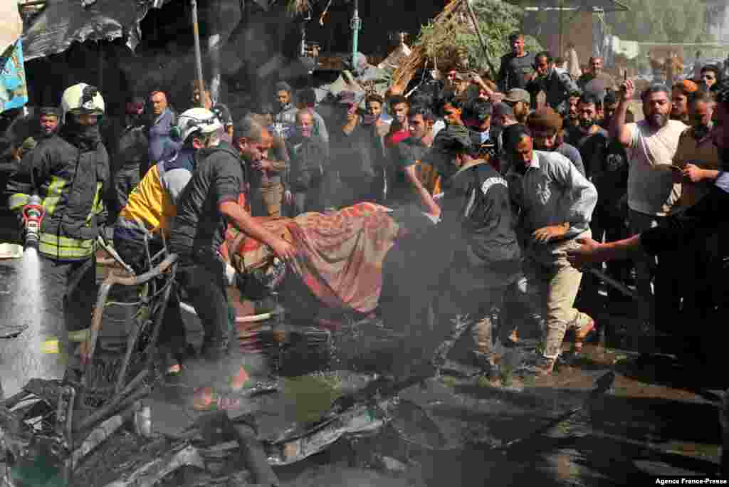 Civil defense members evacuate the body of a victim killed in a car bombing in Syria's rebel-held northern city of Afrin.