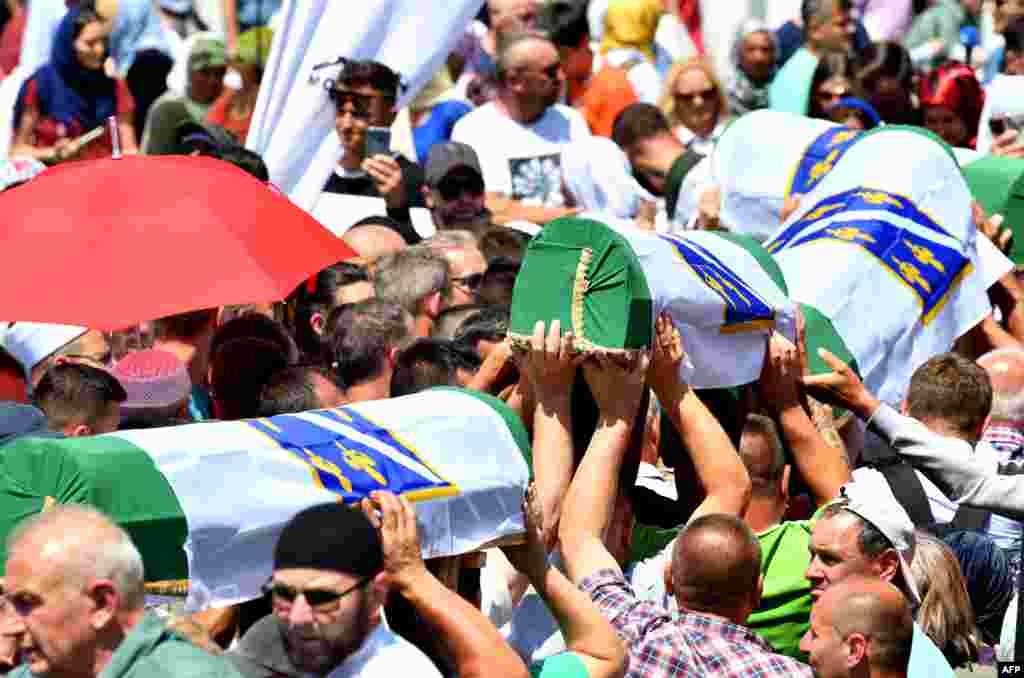Bosnian Muslims carry caskets of the 33 newly identified bodies of the 1995 Srebrenica massacre before their inhumation at the Potocari memorial cemetery near the Eastern-Bosnian town of Srebrenica.