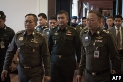Thai Army Lieutenant General Manas Kongpan, center, is surrounded by police officers as he turns himself in at the police headquarters in Bangkok, June 3, 2015.