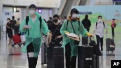 身穿防護服和戴口罩的旅客抵達香港國際機場。 （2020年3月23日）