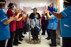 Margaret Keenan, 90, is applauded by staff as she returns to her ward after becoming the first patient in the UK to receive the Pfizer-BioNTech COVID-19 vaccine, at University Hospital, Coventry, England.