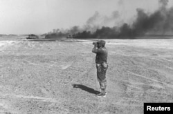 FILE - Israeli Major General Ariel Sharon watches an aerial drop through his binoculars in the Sinai Peninsula, then occupied by Israel, during the Middle East War, June 8, 1967.