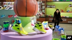 In this Friday, Feb. 1, 2019, photo, a guide stands near a basketball shoe display in a product exhibition room at the Ryuwon Shoe Factory that specializes in sports footwear, in Pyongyang, North Korea. (AP Photo/Dita Alangkara)