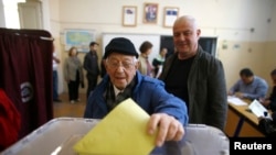 Seorang pria memasukan kertas suara di sebuah TPS saat referendum di kota Izmir, Turki, 16 April 2017. REUTERS / Osman Orsal