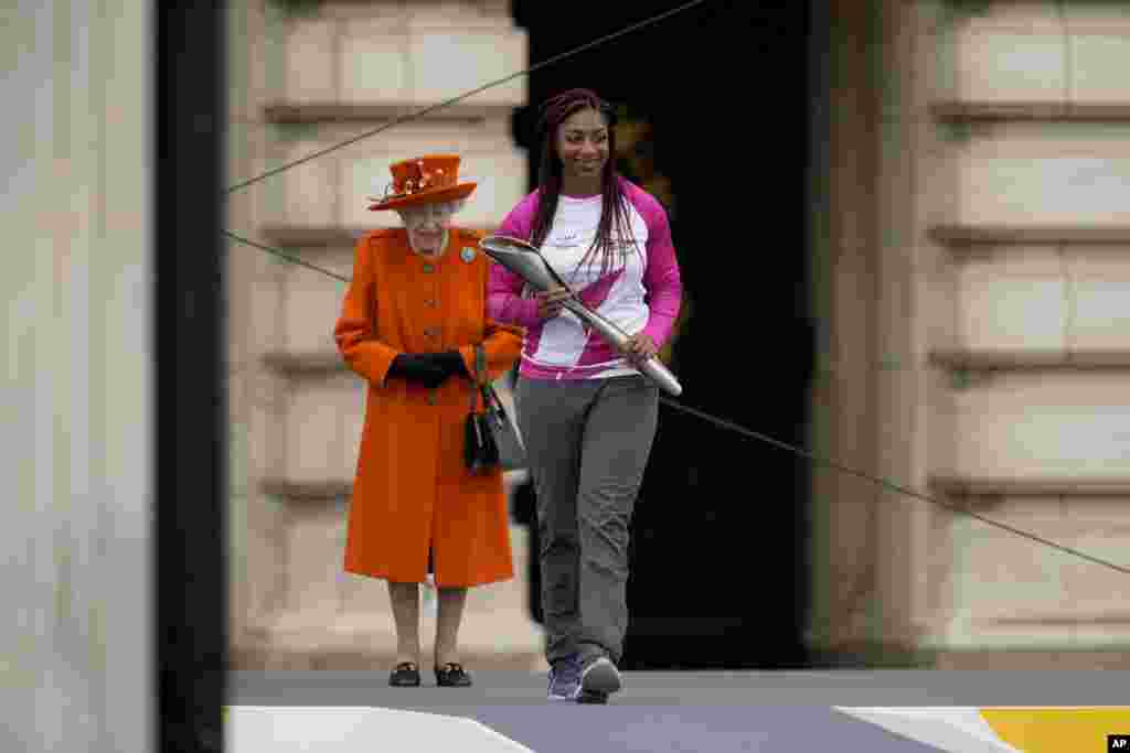 Baton bearer Kadeena Cox of Britain, who won two gold medals at the Rio 2016 Paralympic Games, receives&nbsp; from Queen Elizabeth II&nbsp;the baton&nbsp;to be used&nbsp;at the Birmingham 2022 Commonwealth Games Queen's Baton Relay event, outside Buckingham Palace in London.