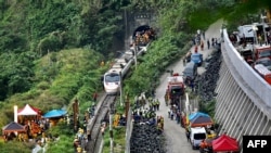 This photo shows rescue workers at the site where a train derailed inside a tunnel in the mountains of Hualien, eastern Taiwan on April 2, 2021. (Photo by Sam Yeh / AFP)