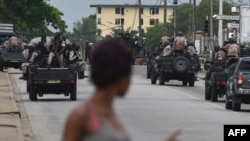 A woman walks past Ivorian soldiers patroling by Ivory Coast's army headquarters, the Gallieni military camp, after they fired shots into the air in Abidjan, May 12, 2017.