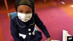 In this, May 2, 2017 photo, Amira Hassan plays in the waiting room at the specialty clinic at Children's Minnesota in Minneapolis. Hassan went to the hospital's clinic for a routine wellness check, but had to wear a mask to protect her from measles after 