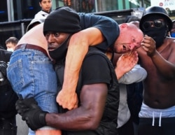 A protester carries an injured counterprotester to safety, near the Waterloo station during a Black Lives Matter protest following the death of George Floyd in Minneapolis police custody, in London, June 13, 2020.
