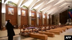 Pastor Paroki Seriate, Don Mario, berdiri dekat jajaran peti jenazah di Gereja San Giuseppe di Seriate, dekat Bergamo, Lombardy, 26 Maret 2020. (Foto: AFP)