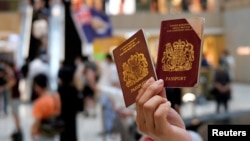 Seorang pengunjuk rasa menunjukkan paspor British National Overseas (BNO) dalam demo menentang undang-undang keamanan nasional baru di Hong Kong, 1 Juni 2020.