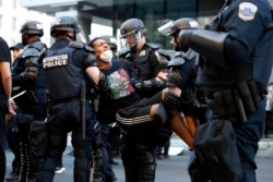 A demonstrator is taken into custody by police after a curfew took effect during a protest over the death of George Floyd, Monday, June 1, 2020, near the White House in Washington.