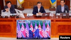 South Korean President Moon Jae-in looks at a TV broadcasting a news report on summit between the U.S. and North Korea during a cabinet meeting at the Presidential Blue House in Seoul, June 12, 2018. 