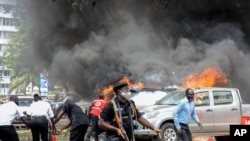 Watu wakizima moto ulioshika magari baada ya mlipuko wa bomu karibu na jengo la bunge Kampala, Uganda, Nov. 16, 2021. (Photo by Ivan Kabuye / AFP)