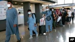 Families evacuated from Kabul, Afghanistan, walk through the terminal before boarding a bus after they arrived at Washington Dulles International Airport, in Chantilly, Virginia.
