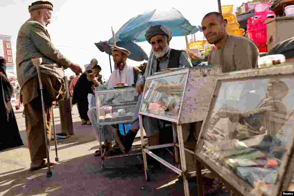 Afghan men sit behind their currency exchange stalls in Kabul.