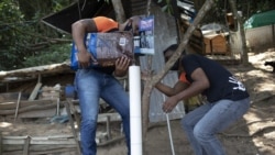 Volunteers from Animal Heart Protectors fill a dispenser with food for cats on Furtada Island, popularly known as “Island of the Cats,” in Mangaratiba, Brazil, Tuesday, Oct. 13, 2020. (AP Photo/Silvia Izquierdo)
