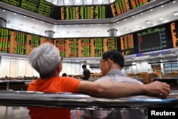 People look at trading boards at a private stock market gallery in Kuala Lumpur, Malaysia, May 14, 2018.