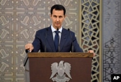 FILE - In a photo released by the official Facebook page of the Syrian Presidency, Syrian President Bashar al-Assad speaks to Syrian diplomats, in Damascus, Syria, Aug. 20, 2017.