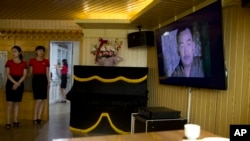 In this Wednesday, Aug. 15, 2018 photo, waitresses stand near a television screen showing a period drama in Pyongyang, North Korea. (AP Photo/Ng Han Guan, File)