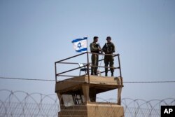 FILE - Israeli soldiers stand guard atop a watch tower along the Israel-Gaza Strip border, May 15, 2018.