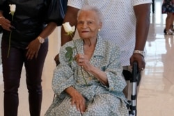 Viola Fletcher, center, the oldest living survivor of the Tulsa race massacre, holds a rose she received as she arrives for a luncheon honoring survivors Saturday, May 29, 2021, in Tulsa, Okla. (AP Photo/Sue Ogrocki)