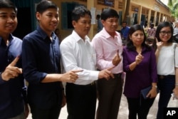 Voters show off their ink-stained fingers after casting their ballots at a polling station in Phnom Penh, Cambodia, July 29, 2018.