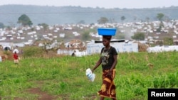 FILE - A Congolese woman, who fled ethnic fighting in the Democratic Republic of Congo on a fishing boat, across Lake Albert, carries belongings on her head at a UNHCR settlement camp in Kyangwali, Uganda, March 20, 2018.