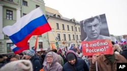 People march in memory of opposition leader Boris Nemtsov, portrait at right, in Moscow, Russia, Sunday, Feb. 26, 2017. Thousands of Russians take to the streets of downtown Moscow to mark two years since Nemtsov was gunned down outside the Kremlin. The poster reads: I love Russia. 