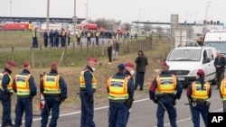 Police officers block the road at the Austrian border in Hegyeshalom, northwestern Hungary, Tuesday, March 17, 2020.