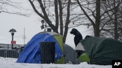 Un hombre permanece de pie junto a varias tiendas de campaña cercanas a un albergue para migrantes, el viernes 19 de enero de 2024, en la Isla Randall de Nueva York.