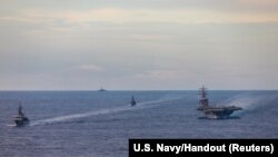 FILE - Japan Maritime Self-Defense Force training ships JS Kashima and JS Shimayuki conduct a passing exercise (PASSEX) with Nimitz-class nuclear-powered aircraft carrier USS Ronald Reagan in the South China Sea, July 7, 2020. 