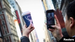 FILE - A company executive photographs a Luckin Coffee cup during the company's IPO at the Nasdaq Market site in New York, May 17, 2019. 